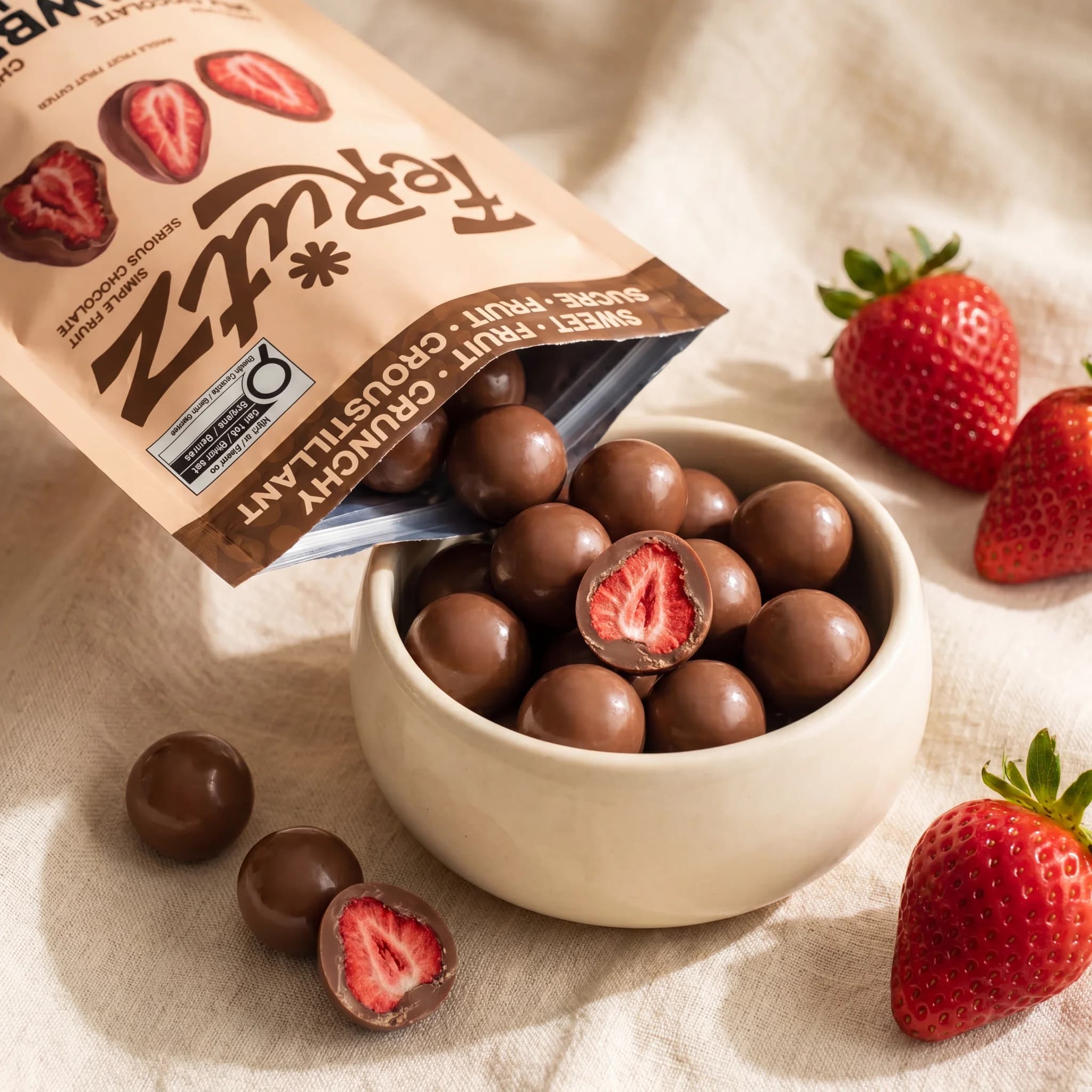 A Ferutz bag pouring milk chocolate bites into a ceramic bowl on cream linen